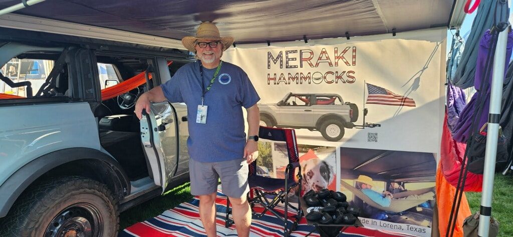 Randall, founder of Meraki Hammocks, at the Meraki Hammocks booth beside a Bronco
